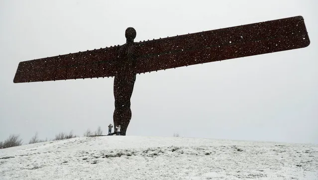 A couple take pictures in the snow next to the Angel of North near Gateshead, Britain, November 30, 2017. (Photo by Lee Smith/Reuters)
