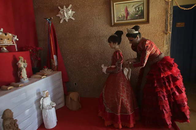 In this November 12, 2017 photo, Luana Borges, right, adjusts her daughter Luana Silva's red dress, as they dress up as Portuguese royalty for the Azorean Culture Festival, which celebrates the culture of the Azores, the Portuguese island chain that lies in the mid-Atlantic, in Enseada de Brito, in Brazil's Santa Catarina southern state. At the climax of the festival, a couple that represents the Portuguese emperor and his wife lead a parade of attendants for a church Mass. (Photo by Eraldo Peres/AP Photo)