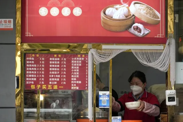 A vendor wearing a mask prepares food in Beijing, Sunday, November 6, 2022. (Photo by Ng Han Guan/AP Photo)