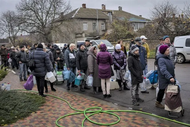 Residents queue to fill containers with drinking water in Kherson, southern Ukraine, Sunday, November 20, 2022. (Photo by Bernat Armangue/AP Photo)