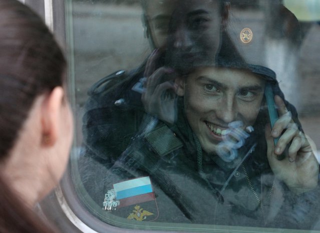 A conscript says goodbye to family members through the window of a train carriage at a local railway station during departure for the garrisons, in Sevastopol, Crimea on November 9, 2022. (Photo by Alexey Pavlishak/Reuters)