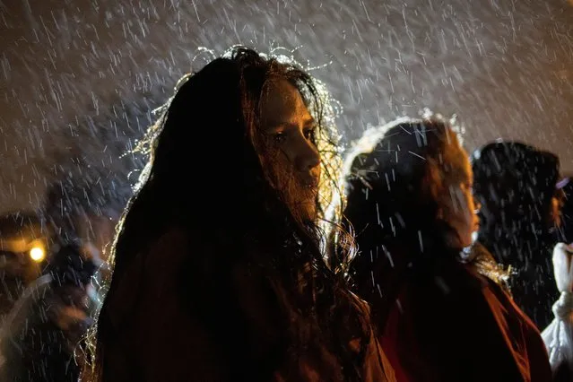 Sulma, 17, from Honduras, endures cold wet weather while standing amid other youth migrants, traveling without adults, as they surrender to border patrol agents after being smuggled across the Rio Grande river from Mexico into Roma, Texas, U.S., November 18, 2022. (Photo by Adrees Latif/Reuters)