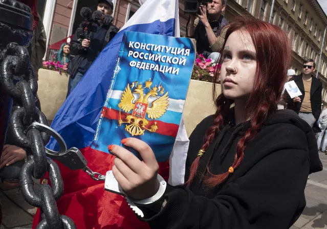 A woman handcuffs herself to a fence while holding a Constitution of the Russian Federation, during a rally supporting Khabarovsk region's governor Sergei Furgal in St.Petersburg, Russia, Saturday, August 1, 2020. (Photo by Dmitri Lovetsky/AP Photo)