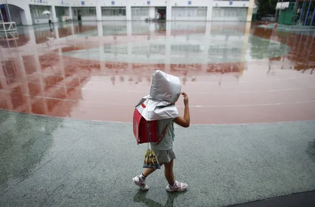 A school girl wearing a padded hood to protect her from falling debris, walks in school field during an earthquake simulation exercise at an elementary school in Tokyo September 1, 2015. (Photo by Toru Hanai/Reuters)
