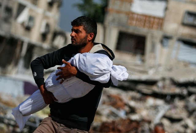 A Palestinian man carries the body of a child killed in Israeli strikes, in Jabalia, in the northern Gaza Strip on May 16, 2025. (Photo by Mahmoud Issa/Reuters)