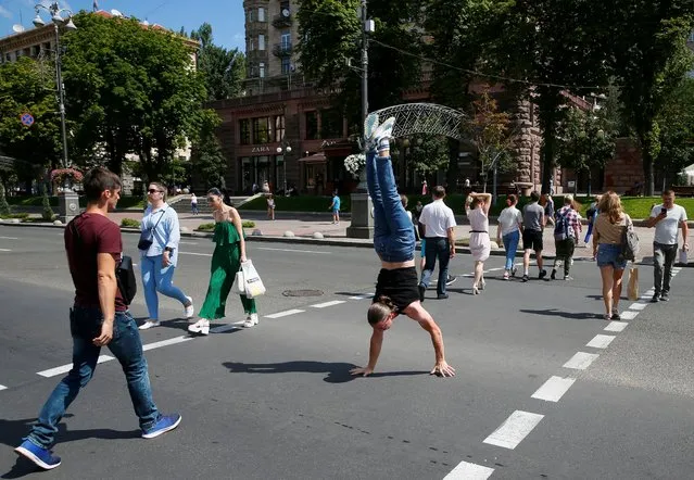 A man walks on his hands as he crosses a street in central Kyiv, Ukraine on August 4, 2020. (Photo by Gleb Garanich/Reuters)