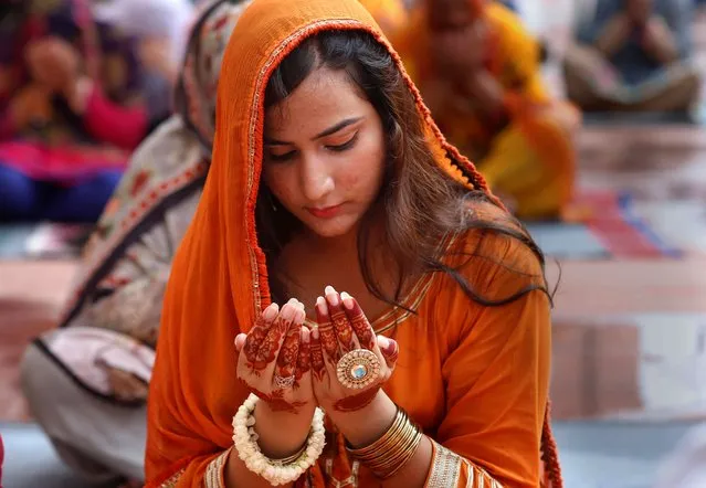 A woman prays during Eid al-Adha prayers at the historical Badshahi Mosque in Lahore, Pakistan, Saturday, August 1, 2020. During Eid al-Adha, or Feast of Sacrifice, Muslims slaughter sheep or cattle and distribute portions of the meat to the poor. (Photo by K.M. Chaudary/AP Photo)