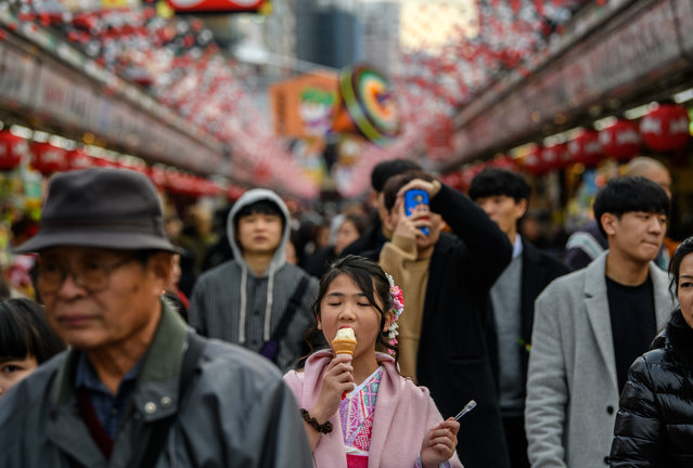 A girl eats an ice cream as she walks along Nakamise-dori, a shopping street near Senso-ji buddhist temple, on January 19, 2018 in Tokyo, Japan. Senso-ji, is Tokyo's oldest temple, dating back to 628, and one of its largest. It is believed to be the most visited spiritual site in the world with over 30 million visitors each year. (Photo by Carl Court/Getty Images)