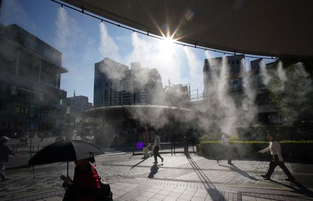 People walk through artificial mist to cool down on a hot day in Tokyo on June 19, 2025. (Photo by Kazuhiro Nogi/AFP Photo)