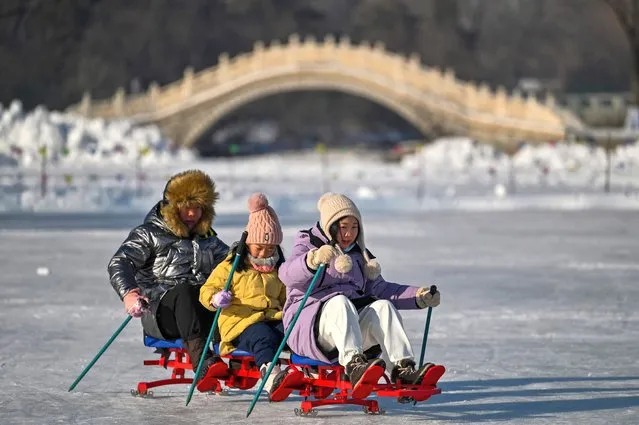 People use a sled over a frozen river at the Harbin Sun Island International Snow Sculpture Art Expo in Harbin, in China's northeastern Heilongjiang province, on January 4, 2023, ahead of the 39th Harbin China International Ice and Snow Festival. (Photo by Hector Retamal/AFP Photo)