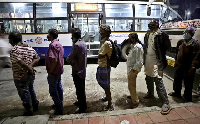 People wearing face masks as a precaution against the coronavirus line up to receive free food distributed by a non-government organization in Bengaluru, India, Saturday, October 31, 2020. Life in India is edging back to pre-virus levels with shops, businesses, subway trains and movie theaters reopening and the country's third-largest state of Bihar with a population of about 122 million people holding elections. (Photo by Aijaz Rahi/AP Photo)