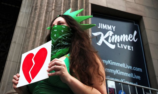 A woman wears a Statue of Liberty costume as she holds an image of a broken heart, outside the El Capitan Entertainment Centre, where “Jimmy Kimmel Live!” is recorded for broadcast, on Hollywood Boulevard in Los Angeles, California on September 18, 2025. (Photo by Daniel Cole/Reuters)