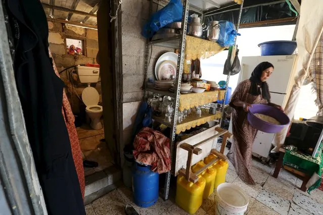 A woman passes near the entrance to a toilet in a makeshift shelter used by a Palestinian family in Khan Younis, in the southern Gaza Strip, October 13, 2015. The family's house was destroyed by, what witnesses said, was Israeli shelling during a 50-day war in the summer of 2014. (Photo by Ibraheem Abu Mustafa/Reuters)