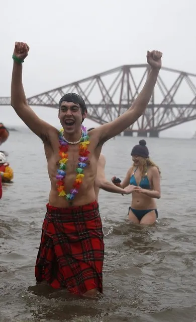 A swimmer in fancy dress rushes out of the water while participating in the New Year's Day Loony Dook swim at South Queensferry, Scotland, January 1, 2015. (Photo by Russell Cheyne/Reuters)