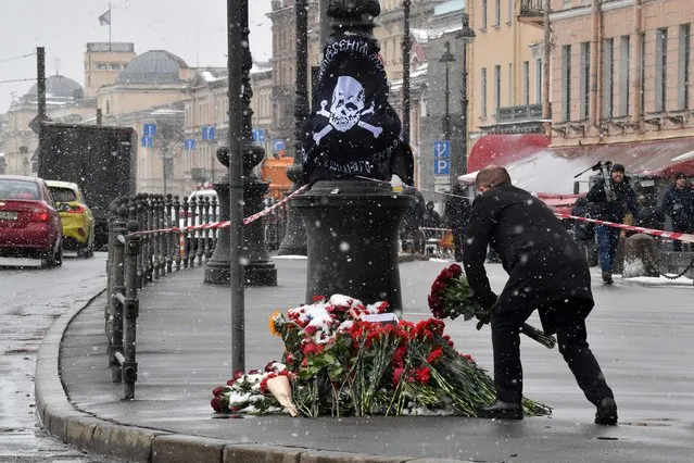 A man lays flowers at a makeshift memorial for Russian military blogger Vladlen Tatarsky, whose real name is Maxim Fomin, who was killed in the April 2 bomb blast in a cafe, by the explosion site in Saint Petersburg on April 3, 2023. (Photo by Olga Maltseva/AFP Photo)