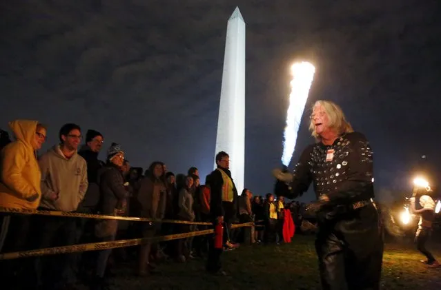Fire performer Stanley Moore spins a fire sword as a crowd watches in front of the Washington Monument during a 48-hour vigil called "Catharsis on the Mall: A Vigil for Healing the Drug War" on the U.S. National Mall in Washington November 22, 2015. (Photo by Jim Bourg/Reuters)