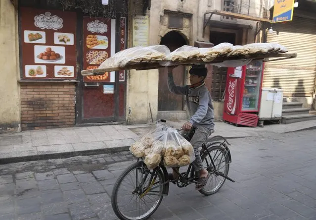 A vendor balances a tray of Egyptian traditional “Baladi” flatbread as he cycles in Old Cairo district, Egypt, Tuesday, March 22, 2022. Experts say they are worried that food security concerns in the Middle East resulting from the war in Ukraine may fuel growing social unrest in countries already on the verge of meltdown. (Photo by Amr Nabil/AP Photo)