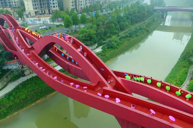 Women in traditional dress stand on a knot-shaped pedestrian bridge in Changsha, China on October 24, 2016. (Photo by Imaginechina/Rex Features/Shutterstock)