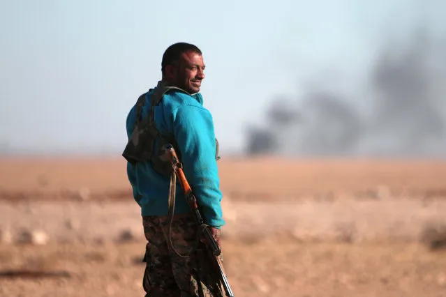 A Syrian Democratic Forces (SDF) fighter stands near rising smoke, north of Raqqa city, Syria November 6, 2016. (Photo by Rodi Said/Reuters)