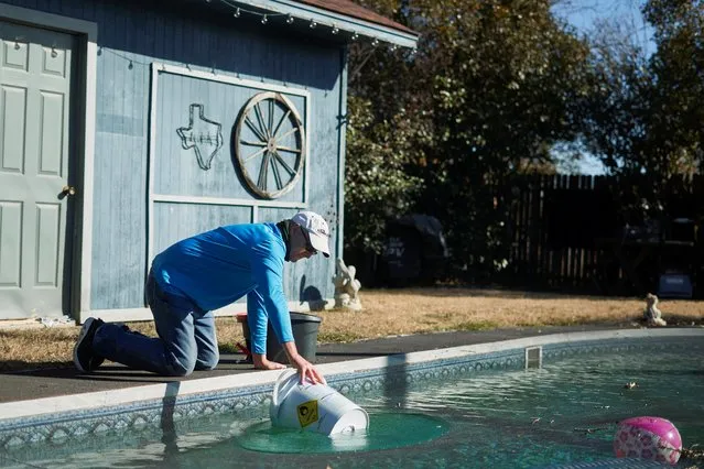 Rodney Roberts fills a bucket with water from his swimming pool to fill toilets in his house after winter weather caused water outages in Mineral Wells, Texas, U.S. February 20, 2021. (Photo by Cooper Neill/Reuters)