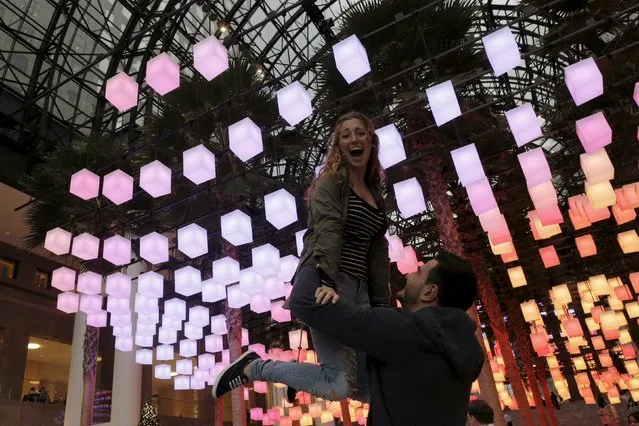 A couple pose in front of a Holiday light display at the Winter Garden in lower Manhattan in New York, December 17, 2015. (Photo by Brendan McDermid/Reuters)