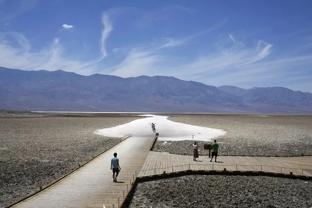 People walk along a boardwalk to salt flats at Badwater Basin, Sunday, July 16, 2023, in Death Valley National Park, Calif. Death Valley's brutal temperatures come amid a blistering stretch of hot weather that has put roughly one-third of Americans under some type of heat advisory, watch or warning. (Photo by John Locher/AP Photo)