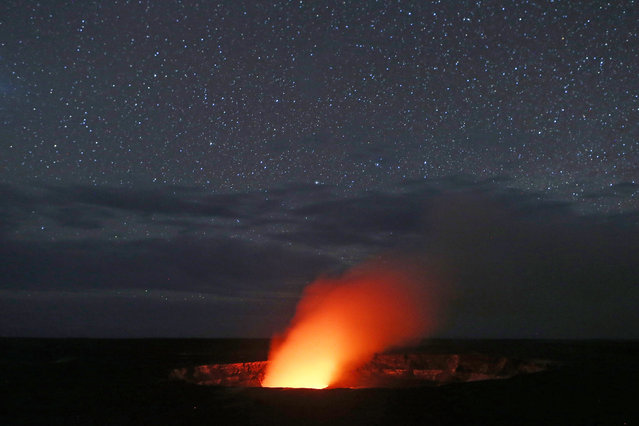 Stars shine above as a plume rises from the Halemaumau crater, illuminated by glow from the crater's lava lake, within the Kilauea volcano summit at the Hawaii Volcanoes National Park on May 9, 2018 in Hawaii Volcanoes National Park, Hawaii. The U.S. Geological Survey said a recent lowering of the lava lake at the crater “has raised the potential for explosive eruptions” at the volcano. The volcano has spewed lava and high levels of sulfur dioxide gas into communities, leading officials to order 1,700 to evacuate. Officials have confirmed 26 homes have now been destroyed by lava in Leilani Estates. (Photo by Mario Tama/Getty Images)