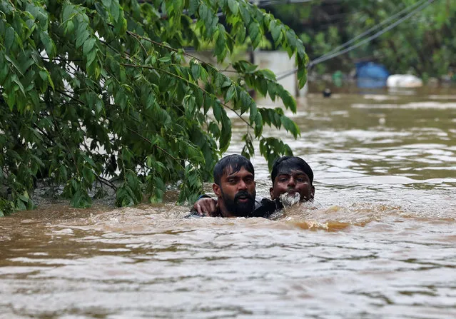 A man rescues a drowning man from a flooded area after the opening of Idamalayr, Cheruthoni and Mullaperiyar dam shutters following heavy rains, on the outskirts of Kochi, India on August 16, 2018. (Photo by Sivaram V/Reuters)