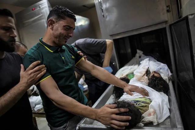 A Palestinian relative mourns over the bodies of four young brothers from the Tanani family who were found under the rubble of a destroyed house following Israeli airstrikes in Beit Lahiya, northern Gaza Strip, Friday, May 14, 2021. (Photo by Khalil Hamra/AP Photo)