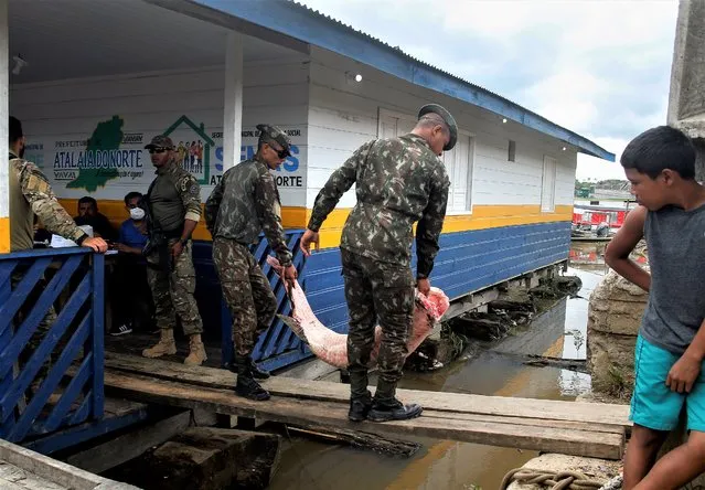 Army soldiers carry seized fish illegally caught in Atalaia do Norte, Amazonas state, Brazil, Saturday, June 11, 2022. According to the police, a wildcat fisherman is the main suspect of the disappearance of British journalist Dom Phillips and Indigenous affairs expert Bruno Pereira, and authorities say illegal fishing near the Javari Valley Indigenous Territory, where Phillips and Pereira went missing last Sunday has raised the tension with local Indigenous groups in the isolated area near the country's border with Peru and Colombia. (Photo by Edmar Barros/AP Photo)