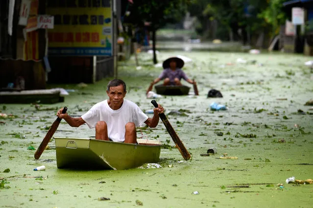 People row in boats through floodwaters in Hanoi's suburban Chuong My district on August 2, 2018. Heavy rains have flooded the area over the past 10 days. (Photo by Nhac Nguyen/AFP Photo)