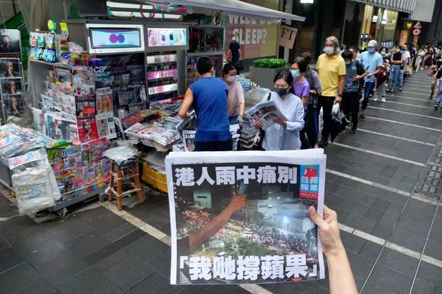 A woman tries to take a picture of last issue of Apple Daily in front of a newspaper booth where people queue up to buy the newspaper at a downtown street in Hong Kong, Thursday, June 24, 2021. Hong Kong's sole remaining pro-democracy newspaper has published its last edition. Apple Daily was forced to shut down Thursday after five editors and executives were arrested and millions of dollars in its assets were frozen as part of China's increasing crackdown on dissent in the semi-autonomous city. (Photo by Vincent Yu/AP Photo)
