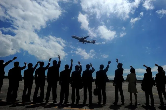 Personnel from the Japanese embassy wave to the plane carrying Japan's Emperor Akihito and Empress Michiko as they depart from the Villamor Airbase in Manila on January 30, 2016. The emperor and empress are on a five-day visit to the Philippines. (Photo by Noel Celis/AFP Photo)