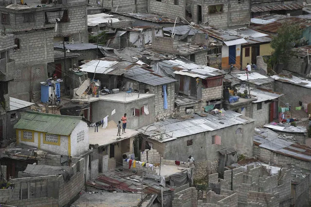 Neighbors stand on a roof in Port-au-Prince, Haiti, Monday, July 12, 2021. (Photo by Matias Delacroix/AP Photo)