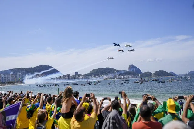 An aerial acrobatic team flies over Copacabana Beach during a military display and rally called by President Jair Bolsonaro to mark the country's bicentennial Independence Day celebrations in Rio de Janeiro, Brazil, Wednesday, September 7, 2022. (Photo by Silvia Izquierdo/AP Photo)