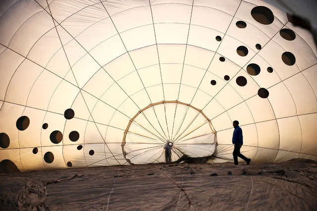 A crew member inspects a partially inflated hot air balloon at the Bristol International Balloon Fiesta in Bristol, Britain, August 4, 202. (Photo by Henry Nicholls/Reuters)