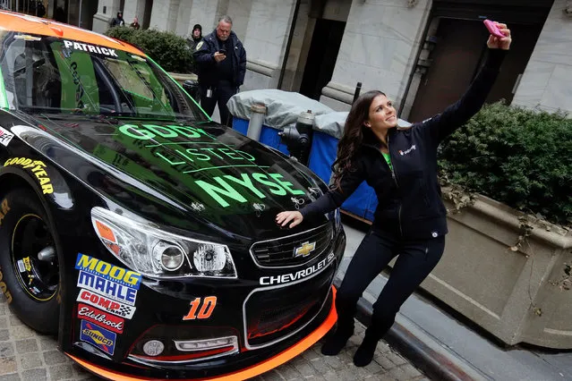 Race car driver Danica Patrick takes a selfie with her car in front of the New York Stock Exchange, before the Go Daddy IPO, Wednesday, April 1, 2015. (Photo by Richard Drew/AP Photo)
