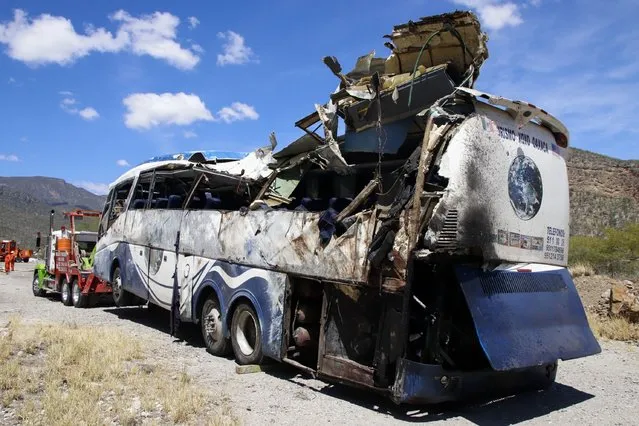 A crashed bus sits attached to a tow truck the side of the road near Villa de Tepelmeme, Oaxaca state, Mexico, Friday, October 6, 2023. At least 18 migrants from Venezuela and Peru died early Friday in the bus crash, authorities said. (Photo by Nemesio Mendez Jiménez/AP Photo)