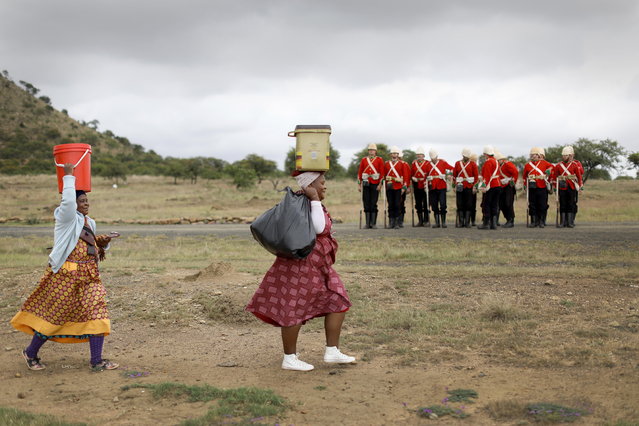 Members of a re-enactment group perform as British Soldiers as local women walk by during the 140th anniversary re-enectment of the Battle of Isandluana in Dundee, South Africa, 25 January 2019. The battle happened during the Anglo-Zulu Wars in 1879 and was the first between the Zulu nation and the British. 20,000 Zulu's attacked 1,800 British soldiers. The Zulu's ultimately overwelmed the British and won the battle. (Photo by Kim Ludbrook/EPA/EFE)