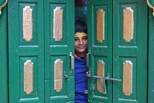 A boy looks through the door of a temple in Ayodhya on December 28, 2023. (Photo by Arun Sankar/AFP Photo)