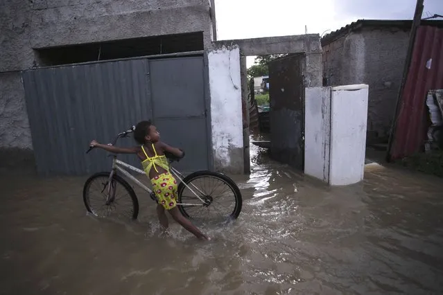 A child pushes a bicycle in a flooded street after deadly, heavy rainfall in Duque de Caxias, Brazil, Sunday, January 14, 2024. (Photo by Bruna Prado/AP Photo)