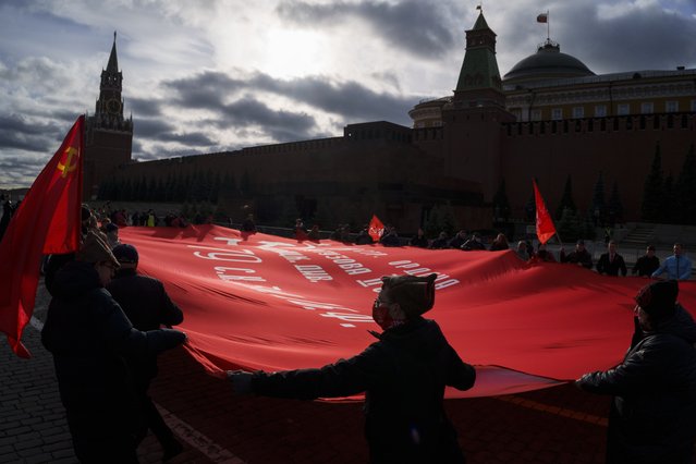 Communist party supporters hold a huge red flag as they walk towards the Tomb of Soviet founder Vladimir Lenin during a demonstration marking the 104th anniversary of the 1917 Bolshevik revolution in Red Square, in Moscow, Russia, Sunday, November 7, 2021. (Photo by Pavel Golovkin/AP Photo)