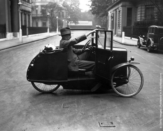 1928: A man cycling a One-Man Car Cycle in a street in the West End of London