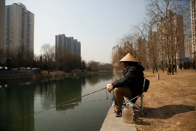 A man fishes on the bank of a canal in front of apartment blocks in Beijing, China February 27, 2017. (Photo by Thomas Peter/Reuters)