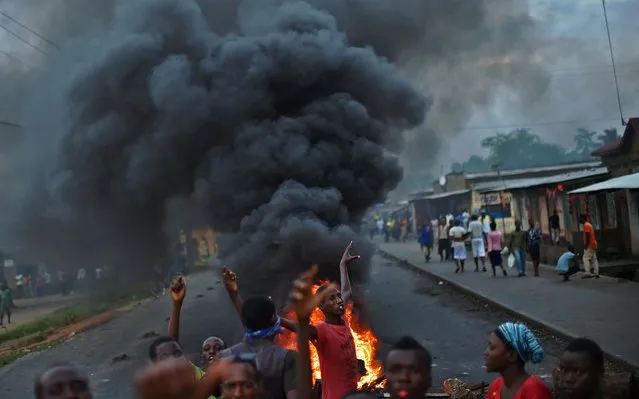 Protestors opposed to the Burundian president Pierre Nkurunziza's  third term in office gather by a burning barricade during a demonstration in the Cibitoke neighborhood of Bujumbura on May 19, 2015.  Thousands of  demonstrators opposed to Burundian President Pierre Nkurunziza defied warning shots and took to the streets of Bujumbura, as their leaders called for them to overcome their fears and continue the fight. (Photo by Carl De Souza/AFP Photo)