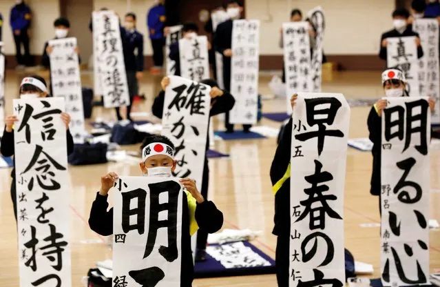 Students wearing protective masks, amid the coronavirus disease (COVID-19) outbreak, show off their writings in an annual New Year calligraphy contest, after last year's was cancelled due to the pandemic, in Tokyo, Japan, January 5, 2022. (Photo by Kim Kyung-Hoon/Reuters)