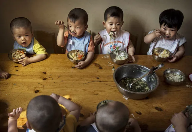 Young orphaned Chinese children eat a meal during feeding at a foster care center on April 2, 2014 in Beijing, China. China's orphanages and foster homes used to be filled with healthy girls, reflecting the country's one-child policy and its preference for sons. Now the vast majority of orphans are sick or disabled. China says it has 576,000 orphans in its child welfare system though outside groups put the number at closer to a million. (Photo by Kevin Frayer/Getty Images)