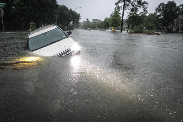 An SUV is stranded in a ditch in a stretch of street flooding during a severe storm, Thursday, May 2, 2024, in Spring, Texas. (Photo by Brett Coomer/Houston Chronicle via AP Photo)