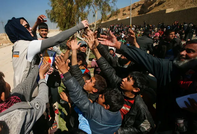 Displaced Iraqis receive food, as Iraqi forces battle with Islamic State militants, in western Mosul, Iraq March 6, 2017. (Photo by Suhaib Salem/Reuters)