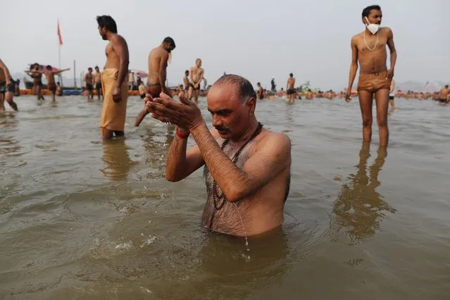 Hindu devotees take ritualistic dips in the Sangam, the confluence of three rivers – the Ganges, the Yamuna and the mythical Saraswati, during Makar Sankranti festival that falls during the annual traditional fair of Magh Mela festival, one of the most sacred pilgrimages in Hinduism, in Prayagraj, India. Friday, January 14, 2022. Tens of thousands of devout Hindus, led by heads of monasteries and ash-smeared ascetics, took a holy dip into the frigid waters on Friday despite rising COVID-19 infections in the country. (Photo by Rajesh Kumar Singh/AP Photo)